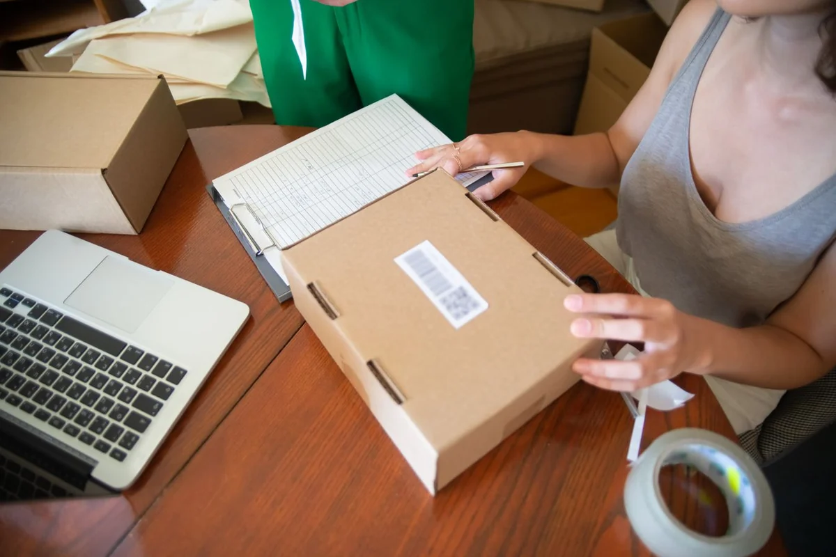 Two small-business owners preparing online orders beside a laptop
